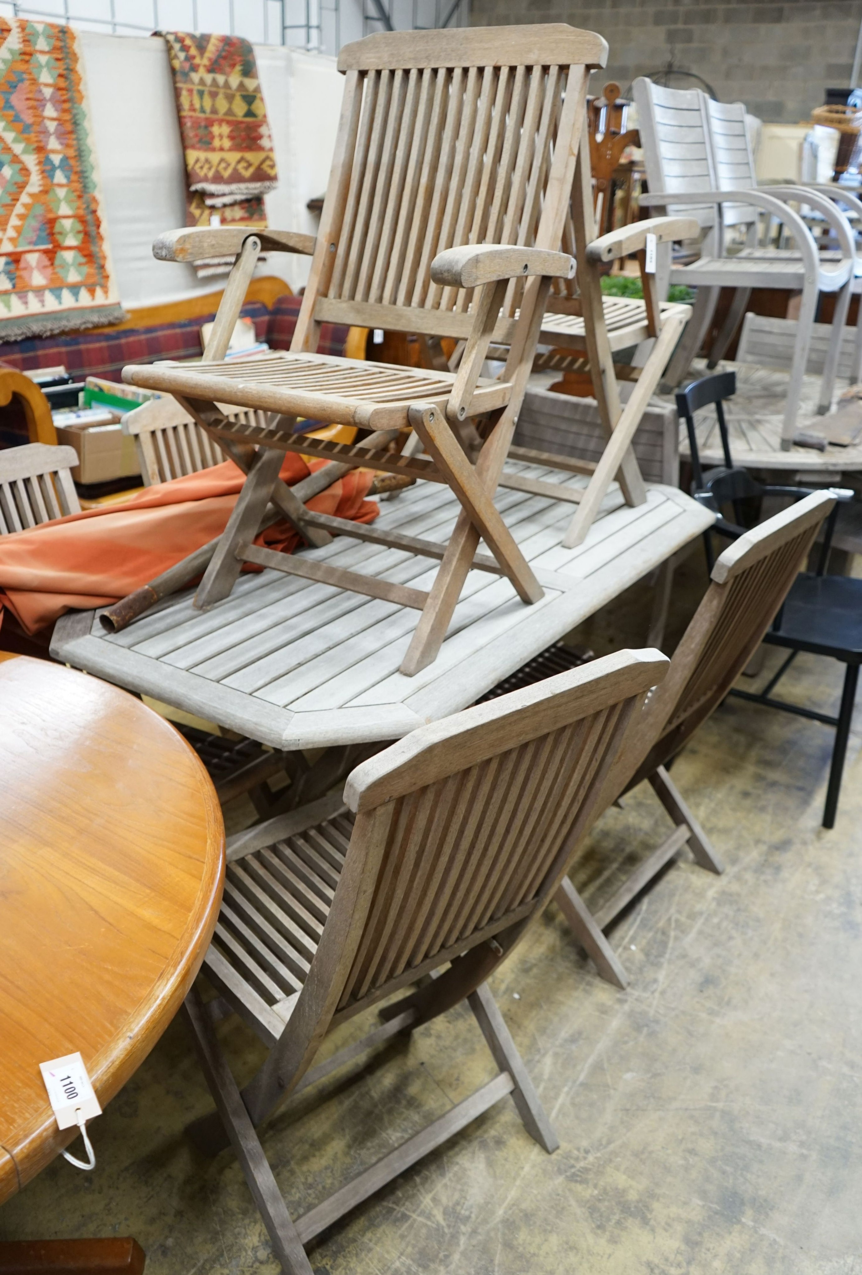 A rectangular weathered teak slatted garden table, length 150cm, depth 79cm, height 72cm, six teak folding chairs, two with arms, parasol and base